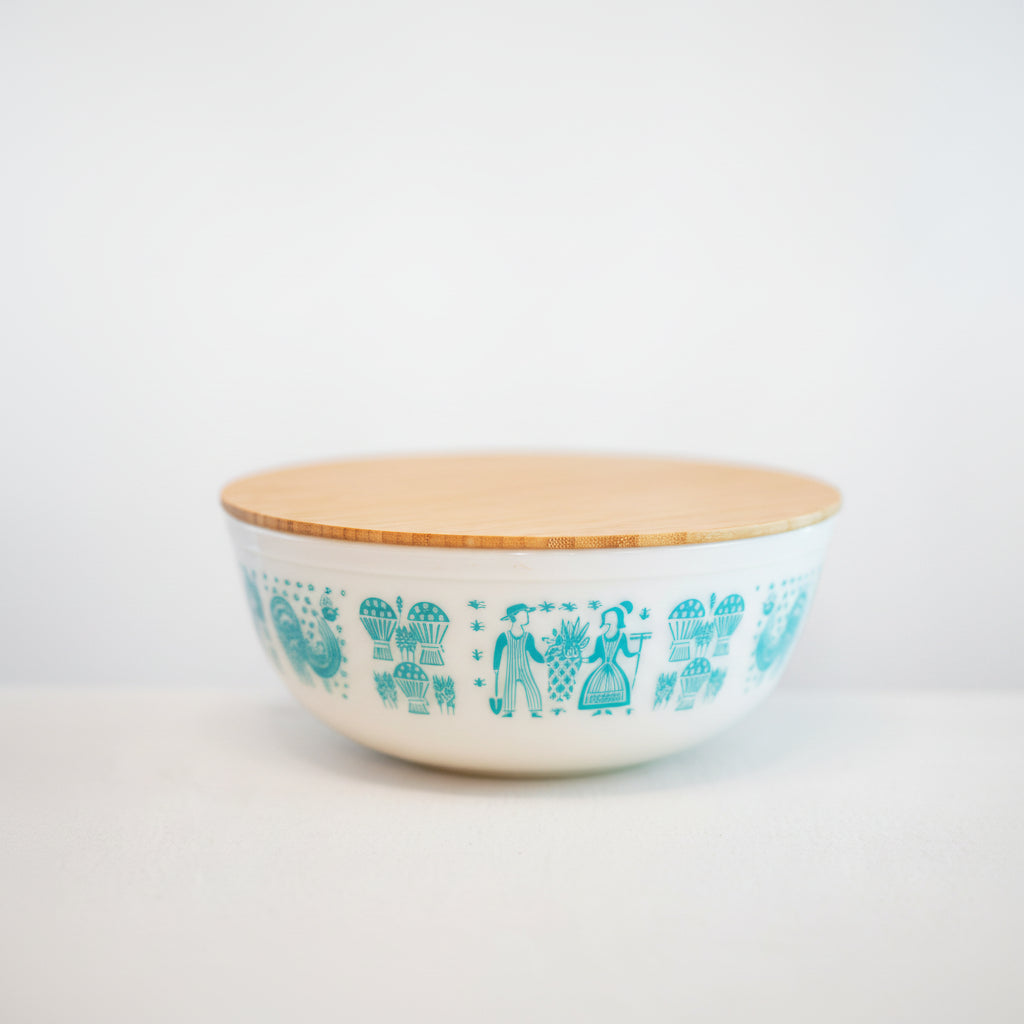 Ceramic bowl with decorative pattern and wooden lid on a white background